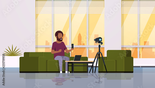guy technology blogger recording video on camera man showing new smartphone functional testing blog concept modern apartment interior full length horizontal