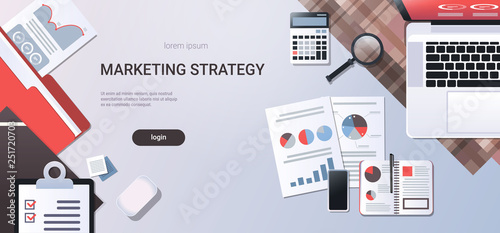 marketing strategy concept workplace desk top angle view laptop with paper documents report finance graph office stuff flat copy space horizontal