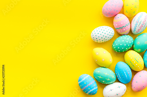 Easter composition. Decorated pastel Easter eggs on yellow background copy space border