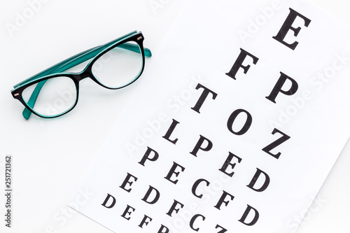 Eye examination. Eyesight test chart and glasses on white background top view