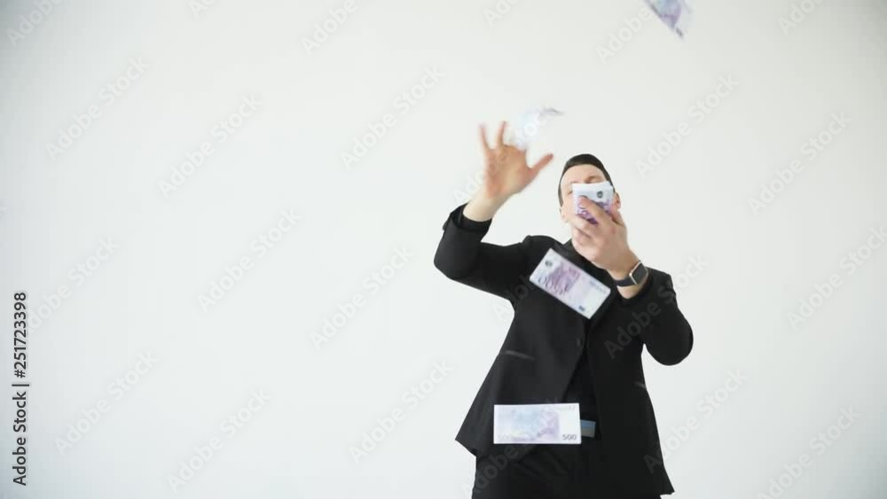 Young happy businessman throwing money. Slow motion. Successful business or winning the lottery. white background Young happy businessman throwing money. Slow motion. Successful business or winning the lottery. white background