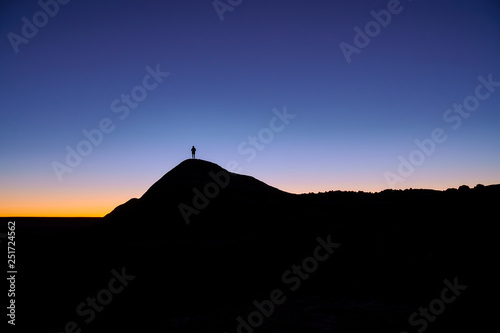 Silhouette of a person standing at the top of the hill before sunrise