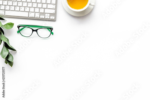 Spring inspiration. Office work desk with computer keyboard, glasses, fresh green spring leaves on white background top view copy space