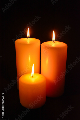 three candles on black background