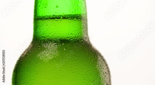 Wet Green Beer Bottle rotating with flowing droplet Closeup macro Advertising shot on white background video