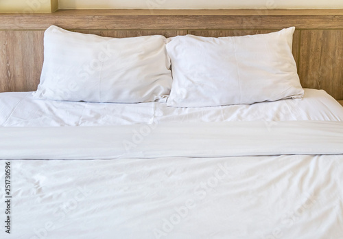 Two white pillows with white bedding sheet on empty bed in bedroom for rest and relax