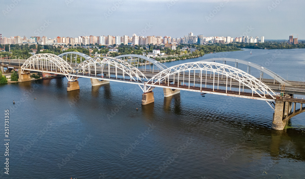 Naklejka premium Aerial top view of automobile and railroad Darnitsky bridge across Dnieper river from above, Kiev (Kyiv) city skyline, Ukraine