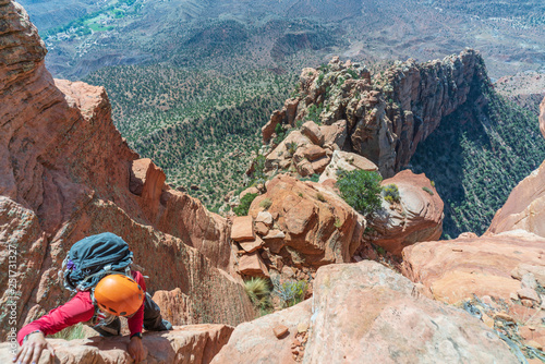 Top down perspective of Woman Climbing Cowboy Ridge in Zion National Park with exposure and heights. Orange Sandstone ridge in Utah