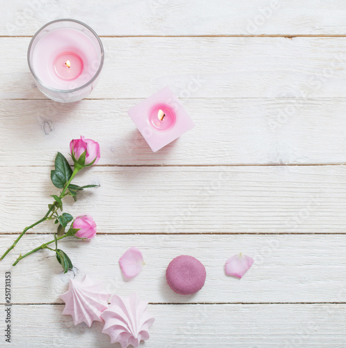 pink candles, roses and macaroons on white wooden background