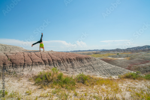 Woman in green shirt does cartwheel in Badlands National Park. 