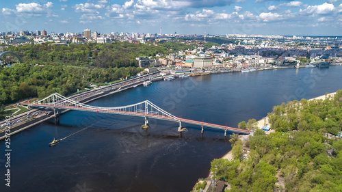 Aerial top view of Kiev city from above, Kyiv skyline, hills, pedestrian Park bridge and Dnieper river cityscape in spring, Ukraine