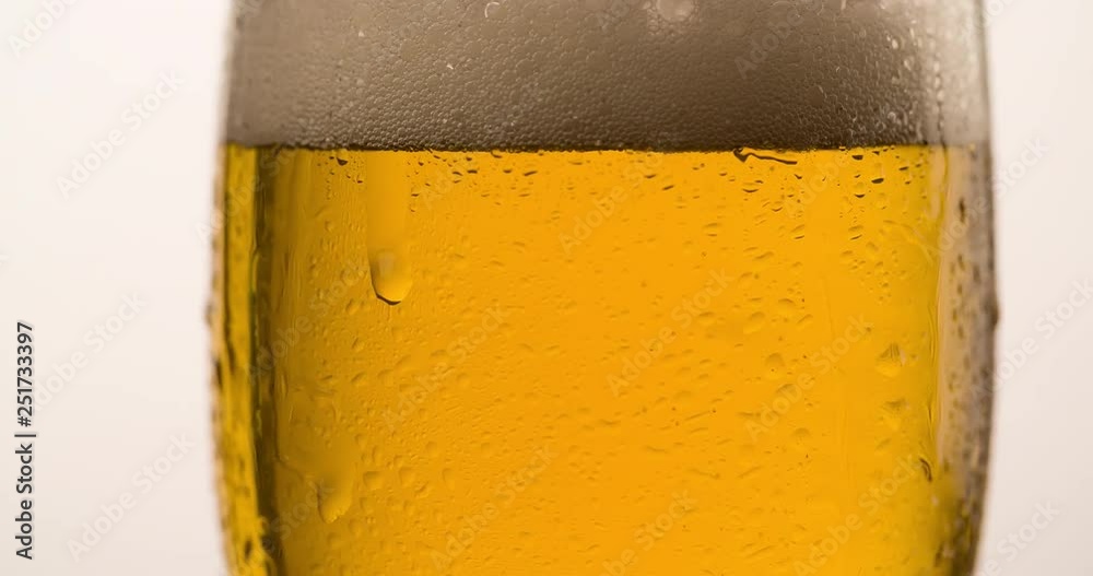Wet Beer Glass rotating with flowing droplet Closeup macro Slow motion Advertising shot on white background 4K video Wet Beer Glass rotating with flowing droplet Closeup macro Slow motion Advertising shot on white background 4K video