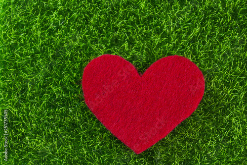 Red felt heart on green background