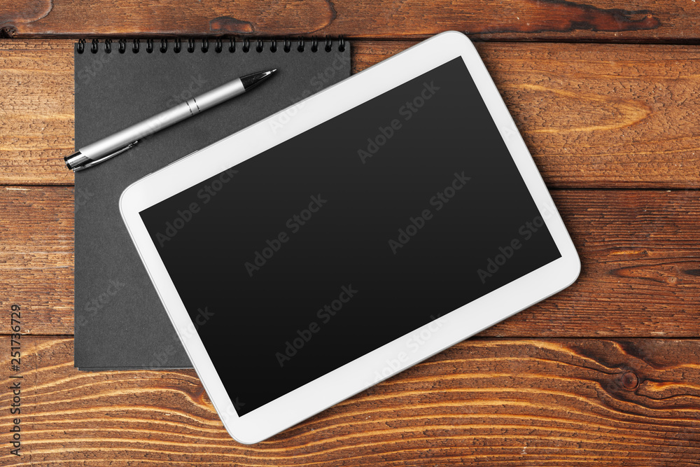 Tablet with notepad on wooden background Tablet with notepad on wooden background