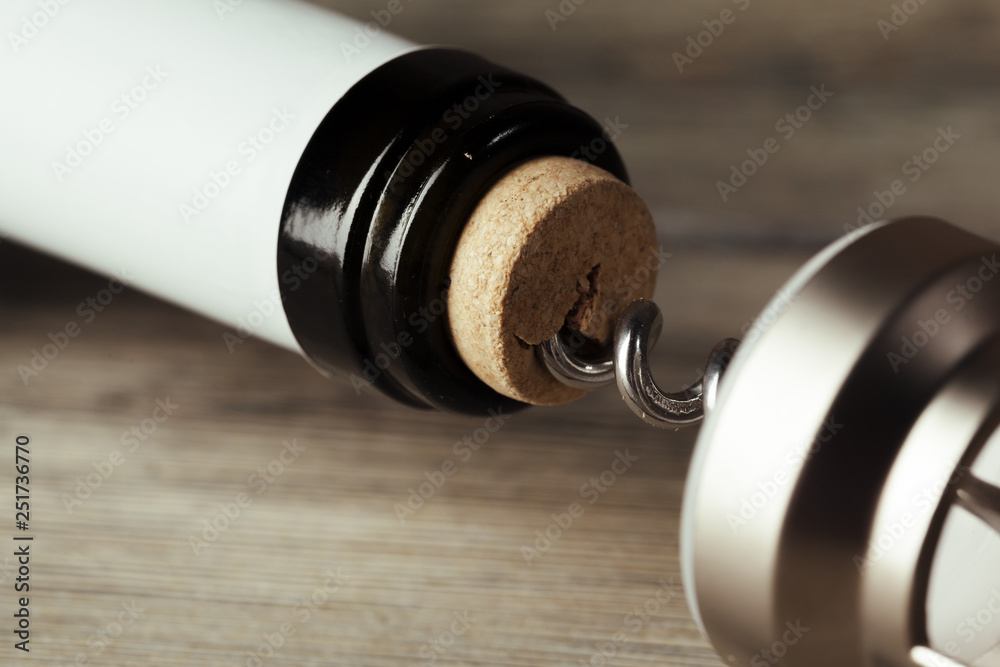 Bottle of wine with corkscrew on wooden background Bottle of wine with corkscrew on wooden background