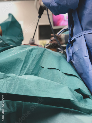 Surgeons using surgical instruments for keyhole surgery, watching the monitor which displays images from inside the patient's abdomen - operating theatre with lights in the background.  photo