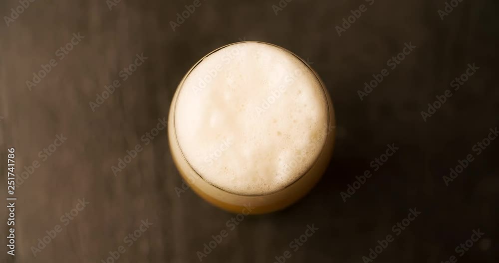 Beer Foam pours out of the glass and flows down Top View Closeup Slow motion 4K video