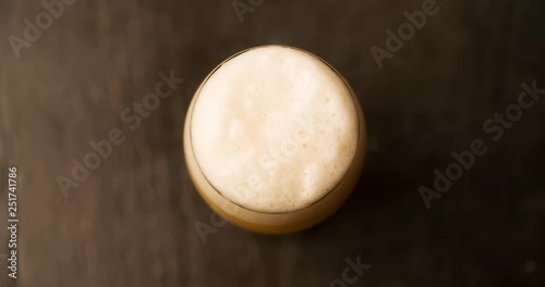 Beer Foam pours out of the glass and flows down Top View Closeup Slow motion 4K video