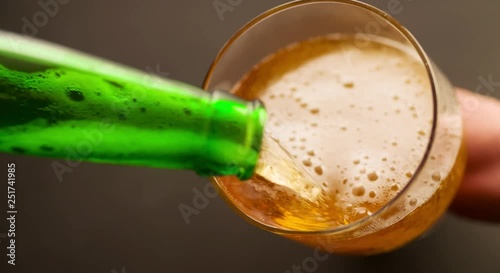 Beer is pouring and foaming in Glass from bottle Top View closeup Slow motion video