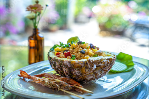 Fried rice with seafood served in a pineapple with colorful background..
