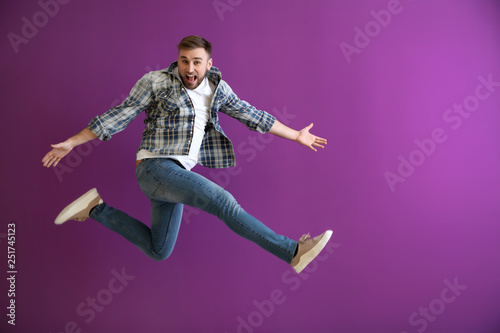 Jumping young man on color ...