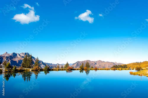 View over blue alpine mountain lake towards swiss alps