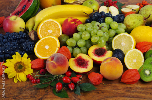 Fototapeta Naklejka Na Ścianę i Meble -  A variety of fruits on the dishes on the table. Grapes, peaches, bananas, kiwi, apples, lemon, orange, pomegranate, pears.