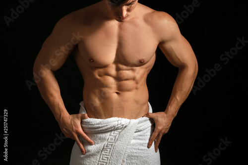 Muscular sexy bodybuilder with towel on dark background