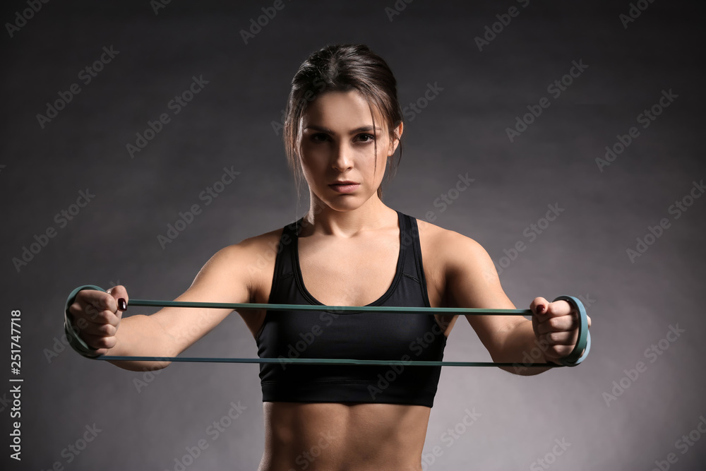 Sporty young woman with resistance band on dark background Sporty young woman with resistance band on dark background