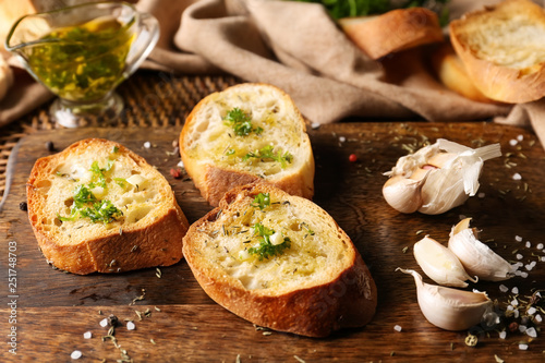 Sliced bread with olive oil, garlic and herbs on wooden table