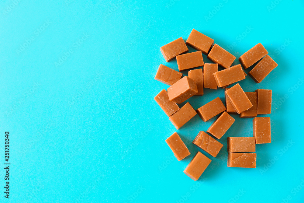 Tasty caramel candies on color background