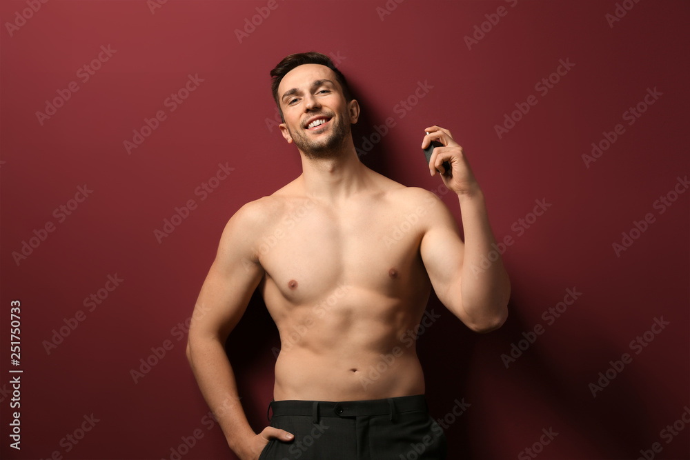 Handsome man with bottle of perfume on color background