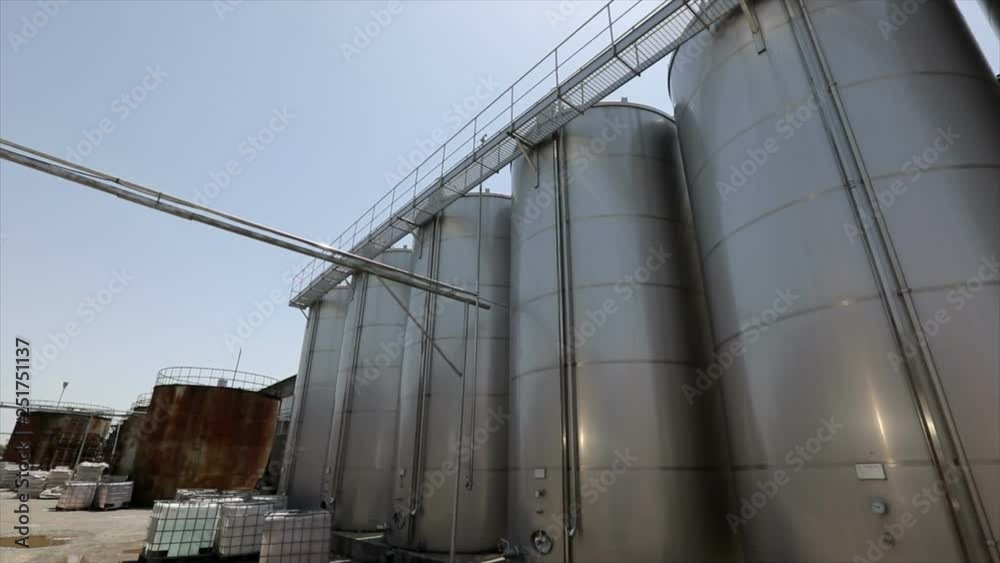 Large stainless steel wine distilling tanks. Silos for wine and beer fermentation . Steel barrels for fermentation of wine in winemaker factory . Dolly , ronin movement a long row of wine vats . Large stainless steel wine distilling tanks. Silos for wine and beer fermentation . Steel barrels for fermentation of wine in winemaker factory . Dolly , ronin movement a long row of wine vats .