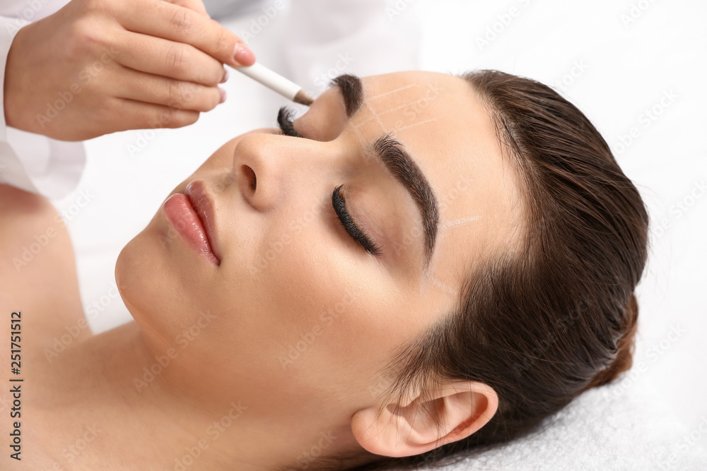 Young woman undergoing eyebrow correction procedure in beauty salon Young woman undergoing eyebrow correction procedure in beauty salon