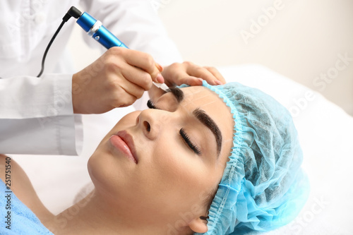 Young woman undergoing procedure of eyebrow permanent makeup in beauty salon