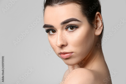 Young woman with beautiful eyebrows on grey background