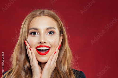 Surprised girl face on red background. Happy woman closeup portrait