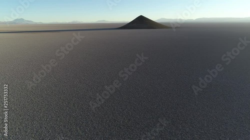 Aerial scene flying towards natural pyramid at white and salar, general view of impressive cone. Sunrise time. Long shade and contrast. Cono de Arita, Salta, Argentina photo