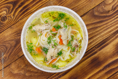 Chicken soup with noodles and vegetables on wooden table. Top view