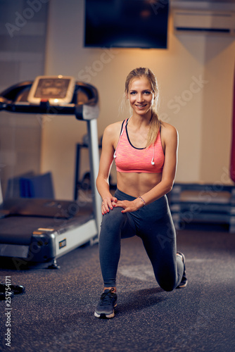 Shaped woman doing exercises for legs and looking down. Gym interior, healthy lifestyle concept.