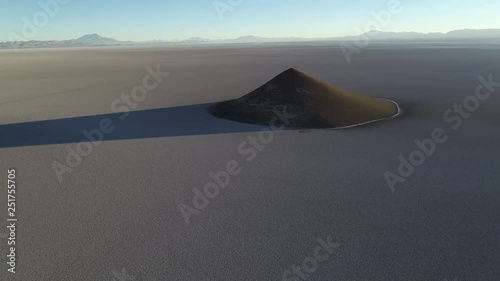 Aerial scene flying towards natural pyramid at white and salar, general view of impressive cone. Sunrise time. Long shade and contrast. Cono de Arita, Salta, Argentina photo