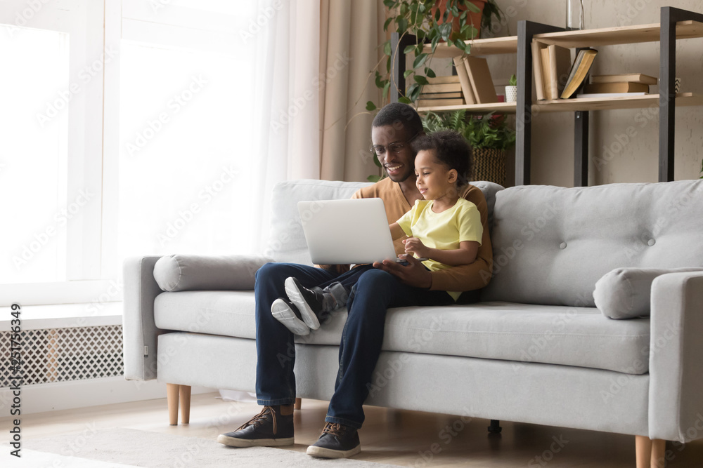 Fototapeta premium Young black father and kid son using laptop at home