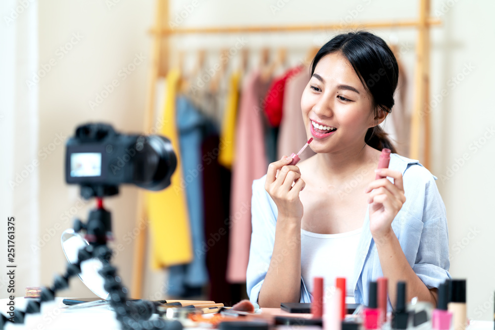 Portrait or headshot of attractive young asian influencer, beauty blogger,  content creator or vlogger girl review make up looking at camera at home.  Asian woman using internet for tutorial live video. foto