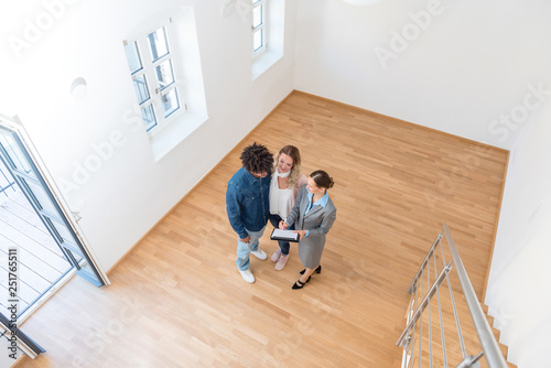 Junges Paar mit Immobilienmaklerin bei Besichtigung einer Mietwohnung 