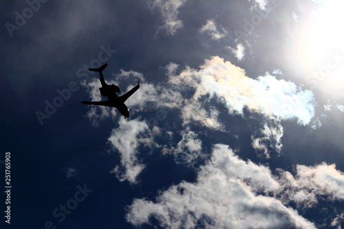 A jet airliner flying under the sun shining in the sky