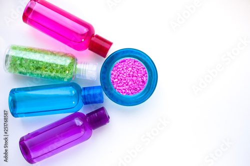 Set of colorful plastic bottles with liquid to care skin inside. Pink and green sea salt. Body care and spa concept. Top view. Close up. Space for a text.