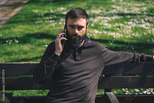 Bearded man using mobile smartphone outside. Blurred background