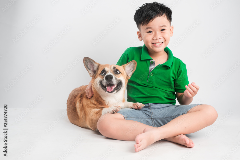 Portrait of a joyful little boy having fun with welsh corgi dog on the floor at studio. Portrait of a joyful little boy having fun with welsh corgi dog on the floor at studio.