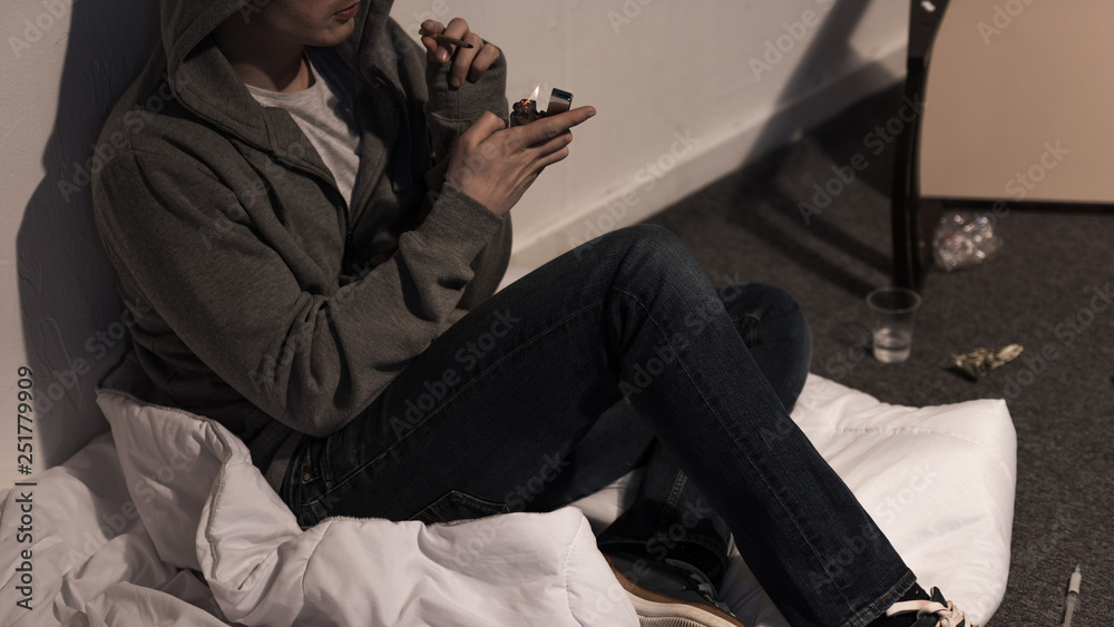 junkie man holding marijuana rolled cigarette and lighter