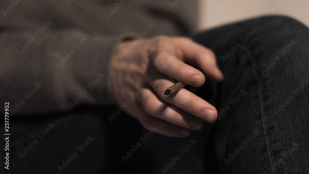 selective focus of male hand with rolled marijuana cigarette